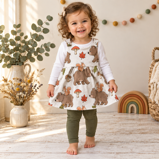 Kind trägt das Latzkleid mit Waldmotiv